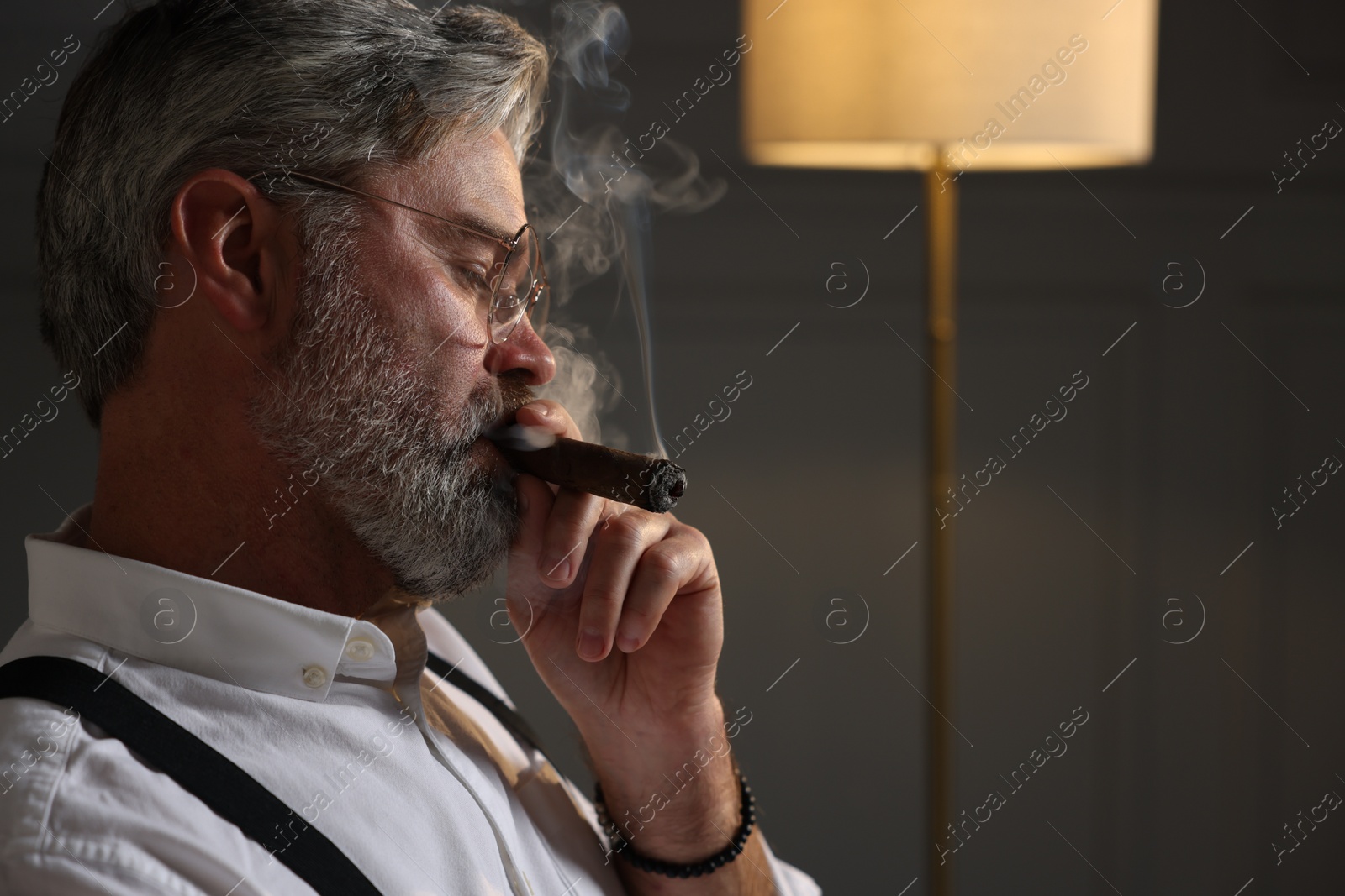 Photo of Bearded man smoking cigar indoors. Space for text