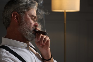 Photo of Bearded man smoking cigar indoors. Space for text