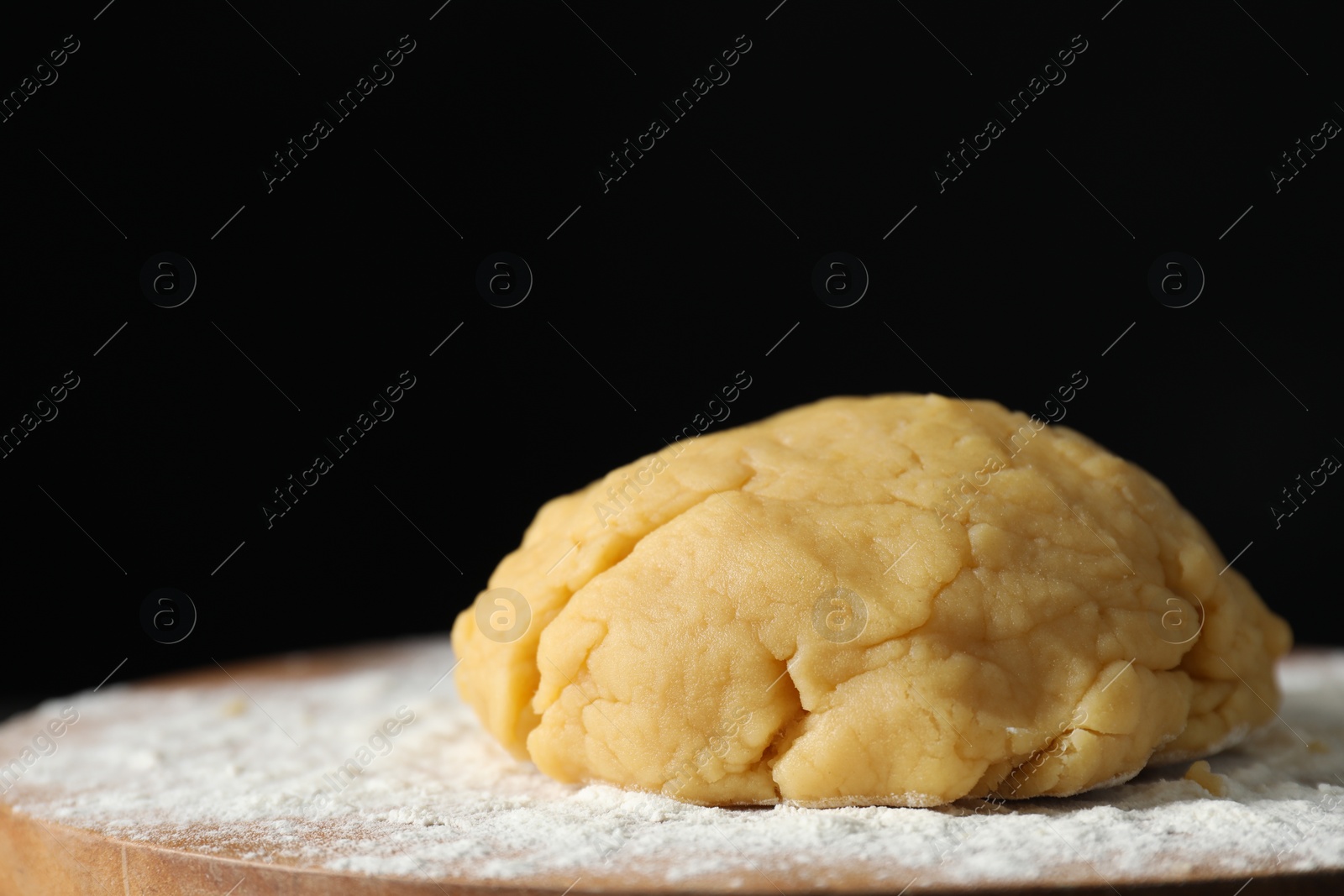 Photo of Making shortcrust pastry. Raw dough and flour on board, closeup. Space for text