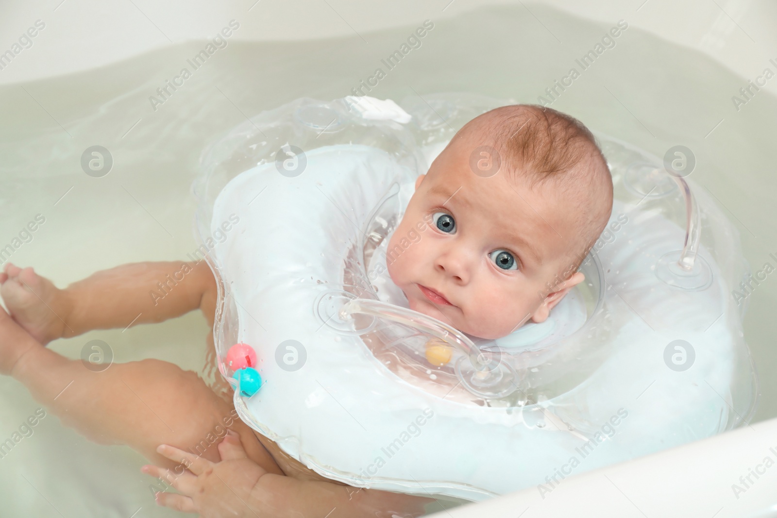 Photo of Cute little baby swimming with inflatable ring in bath