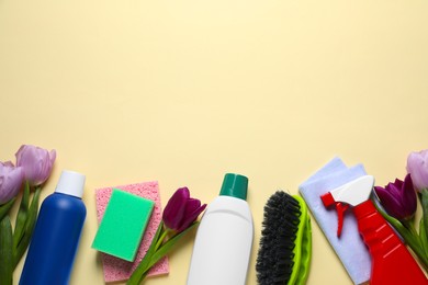 Photo of Spring cleaning. Detergents, flowers, sponge, brush and rag on beige background, flat lay. Space for text
