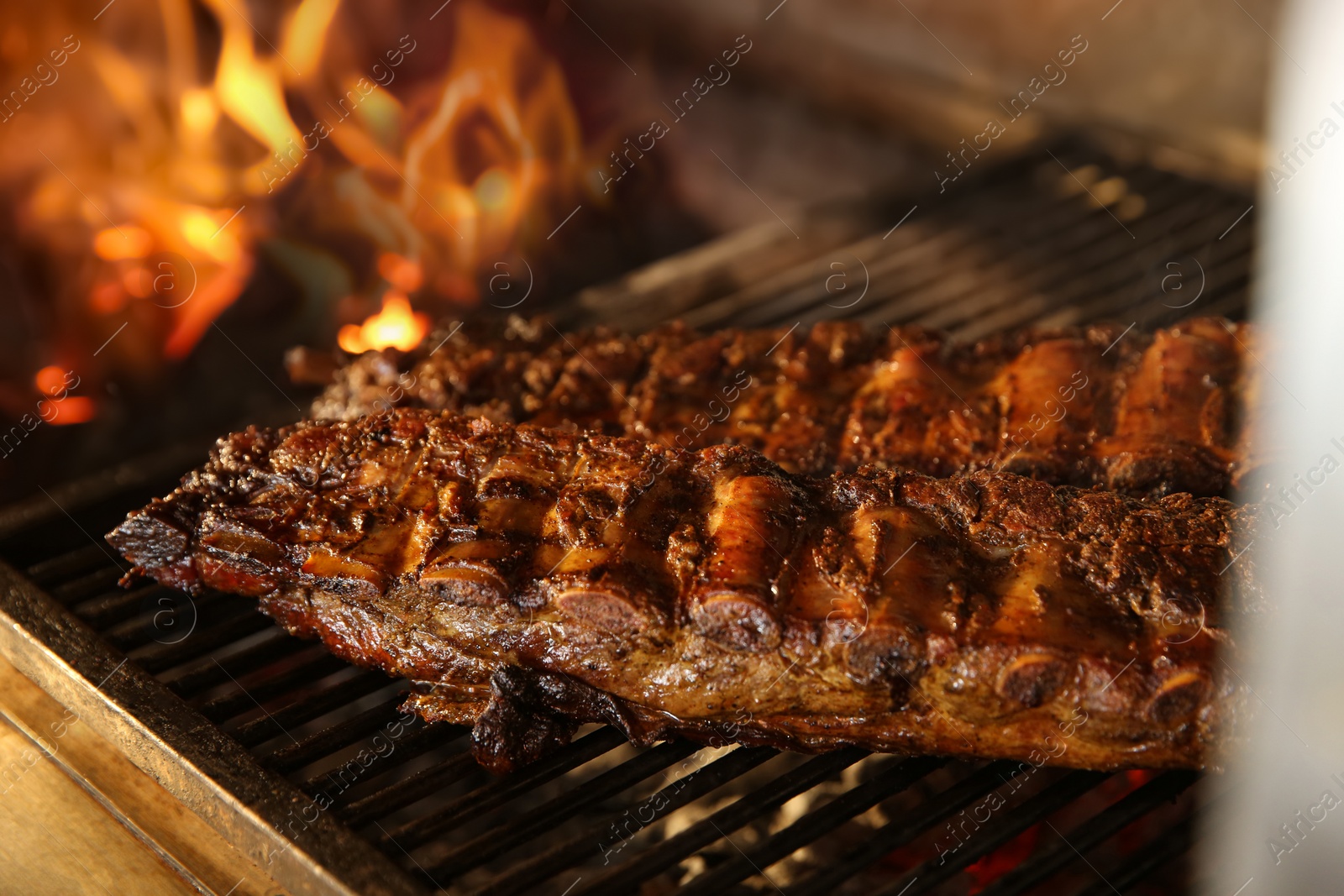 Photo of Grilling grate with tasty pork ribs in oven, closeup