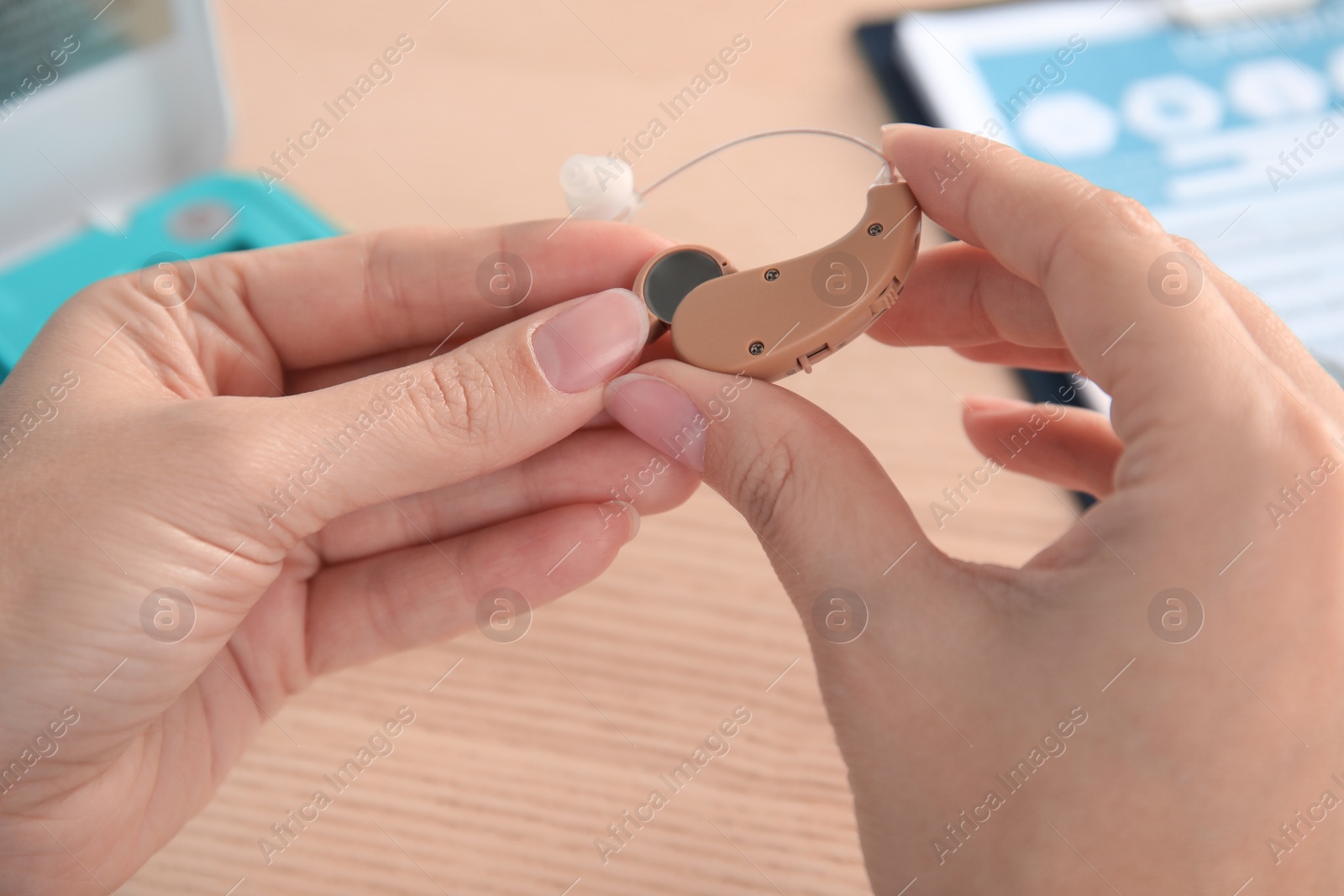 Photo of Doctor putting battery into hearing aid at table, closeup