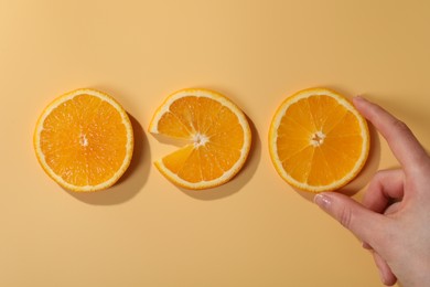 Photo of Woman with slices of juicy orange on beige background, top view