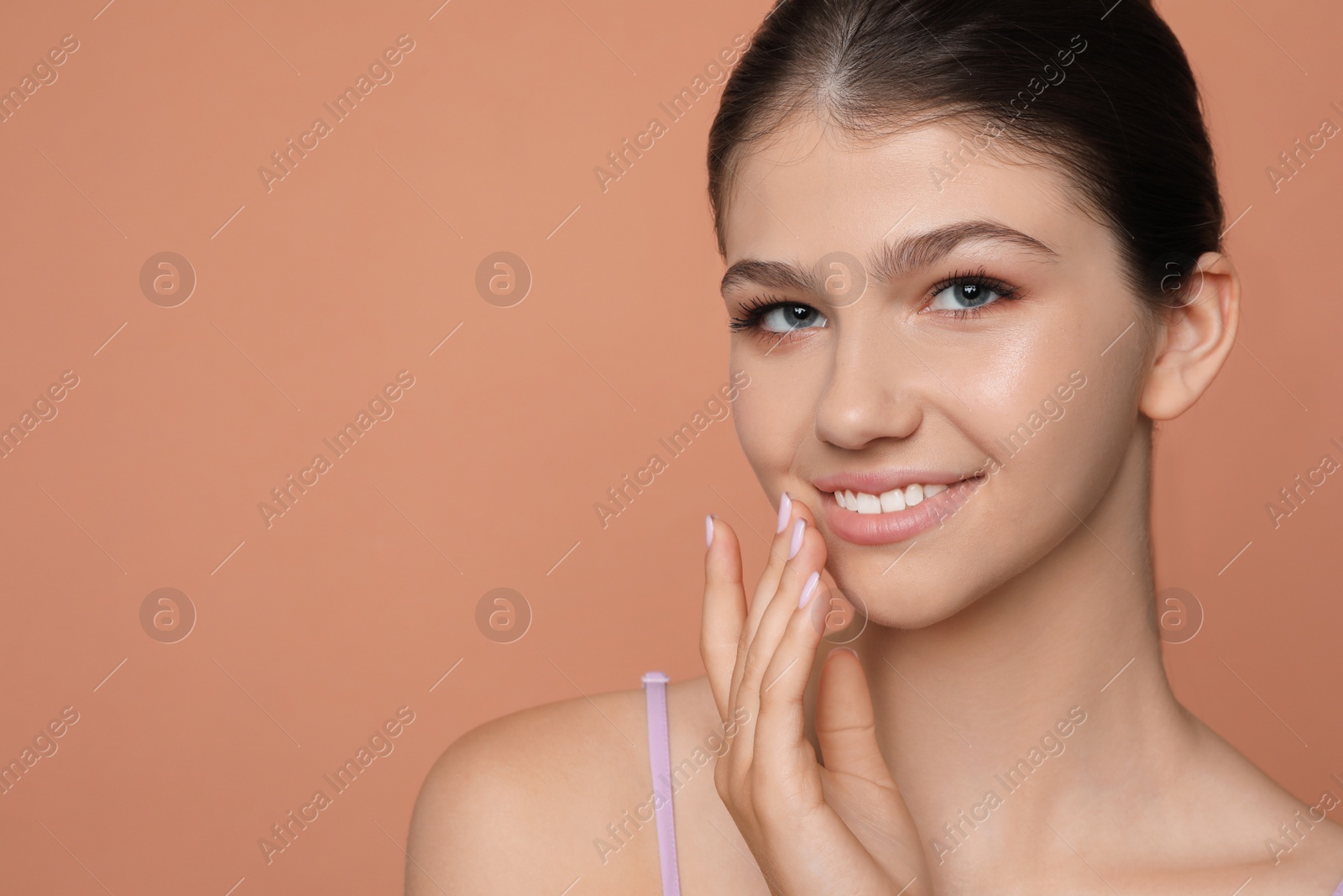 Photo of Pretty girl on pale coral background, space for text. Beautiful face with perfect smooth skin