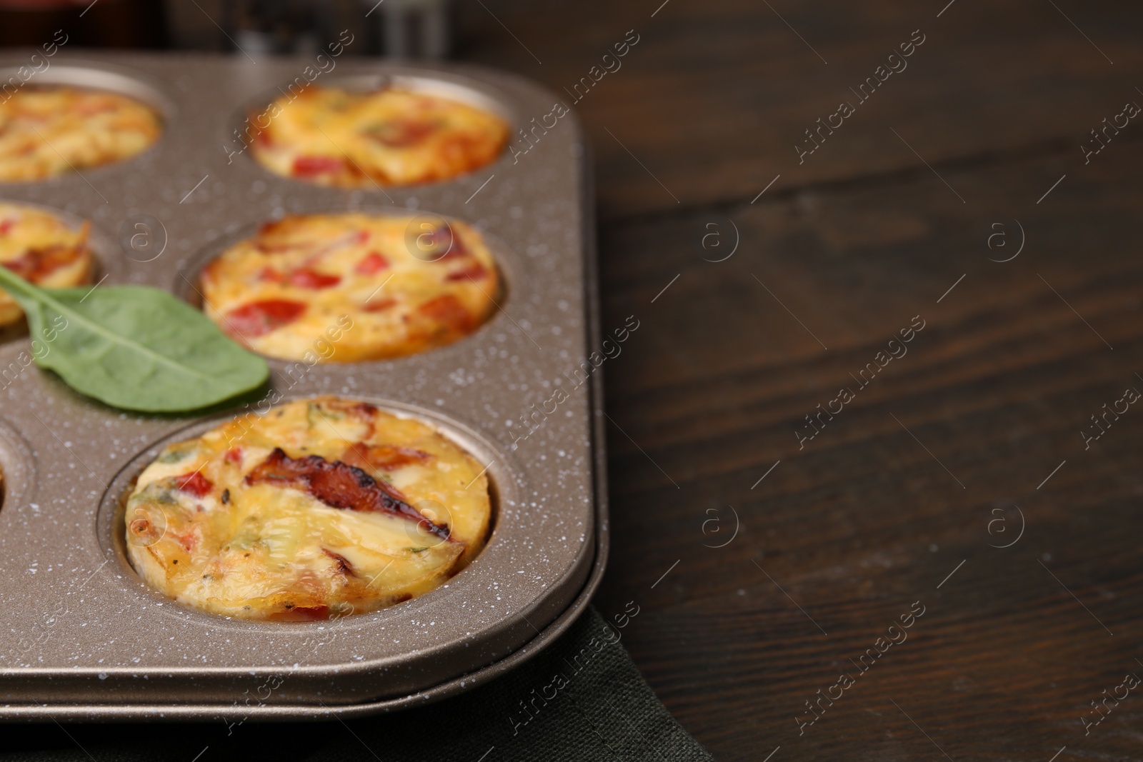 Photo of Freshly baked bacon and egg muffins with cheese in tin on wooden table, closeup. Space for text