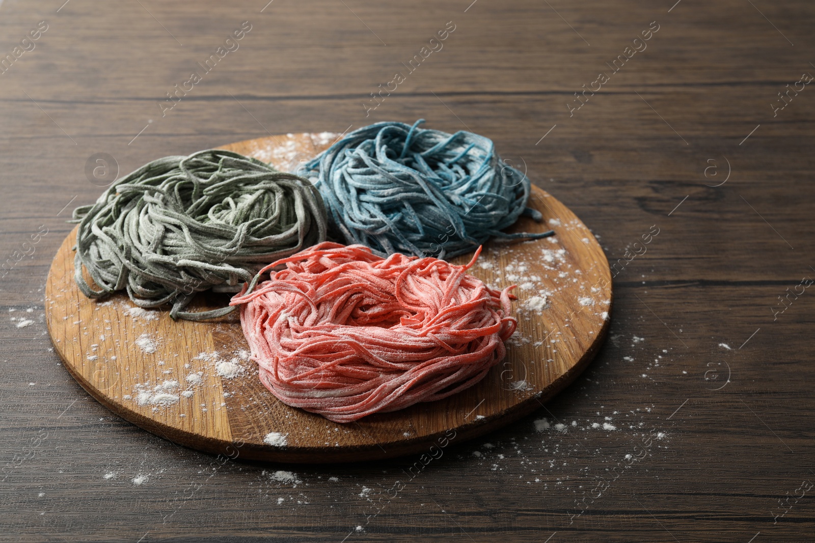 Photo of Rolled pasta painted with food colorings and flour on wooden table