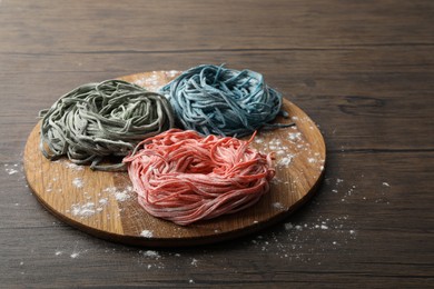 Rolled pasta painted with food colorings and flour on wooden table