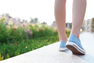 Woman in stylish sneakers walking outdoors, closeup. Urban fashion