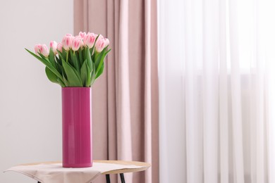 Photo of Beautiful bouquet of fresh pink tulips on table indoors. Space for text