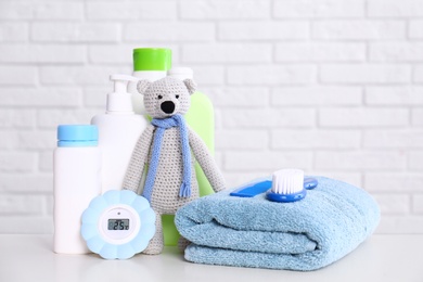 Baby accessories on table near white brick wall. Space for text