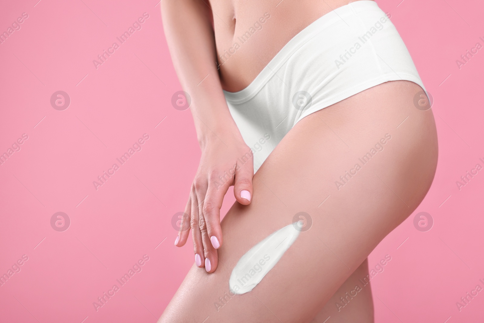 Photo of Woman with smear of body cream on her leg against pink background, closeup. Space for text