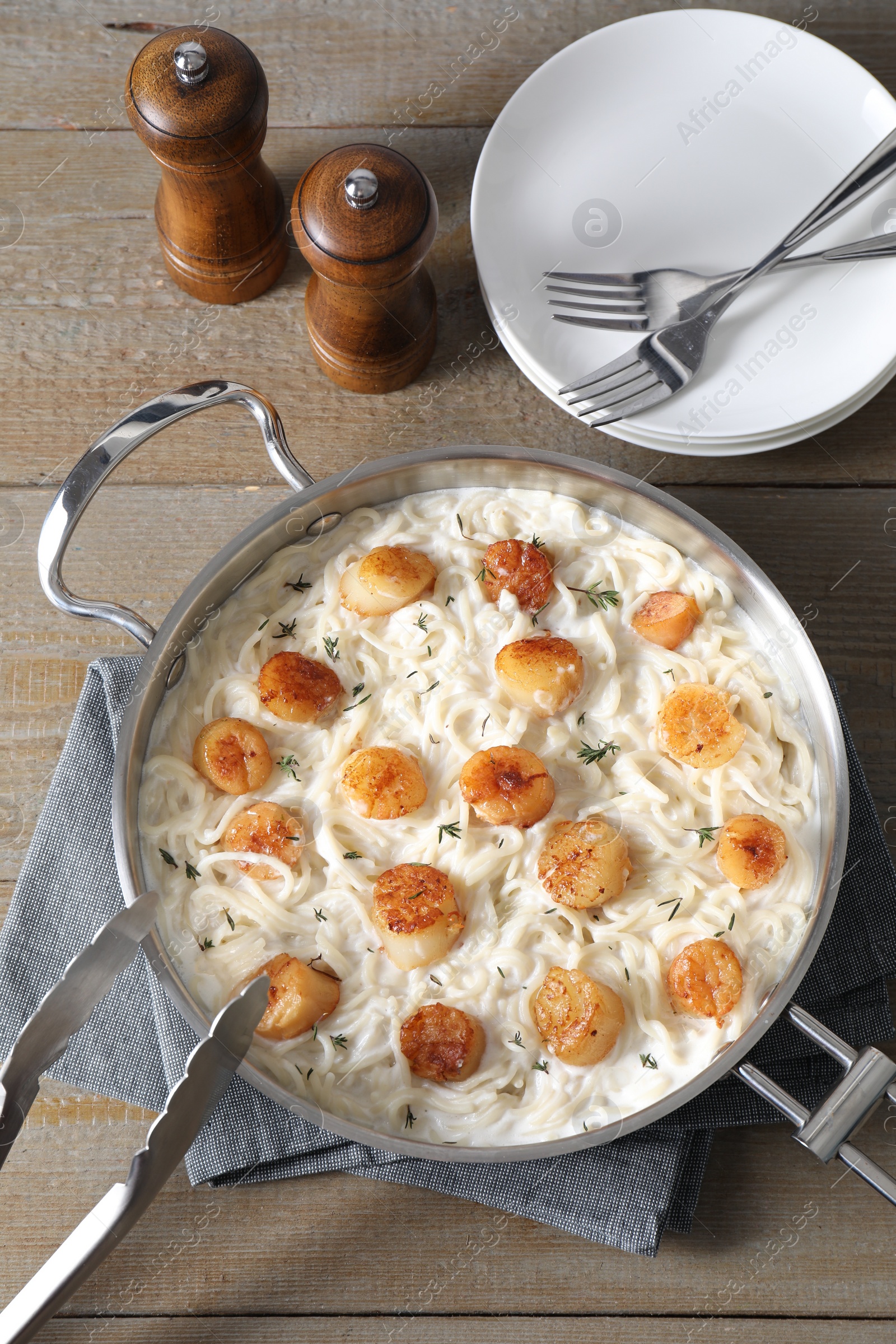 Photo of Delicious scallop pasta served on wooden table, flat lay