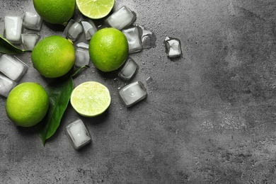 Photo of Composition with fresh ripe limes and ice cubes on gray background, top view