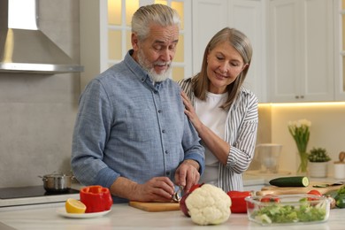 Photo of Happy senior couple cooking together in kitchen