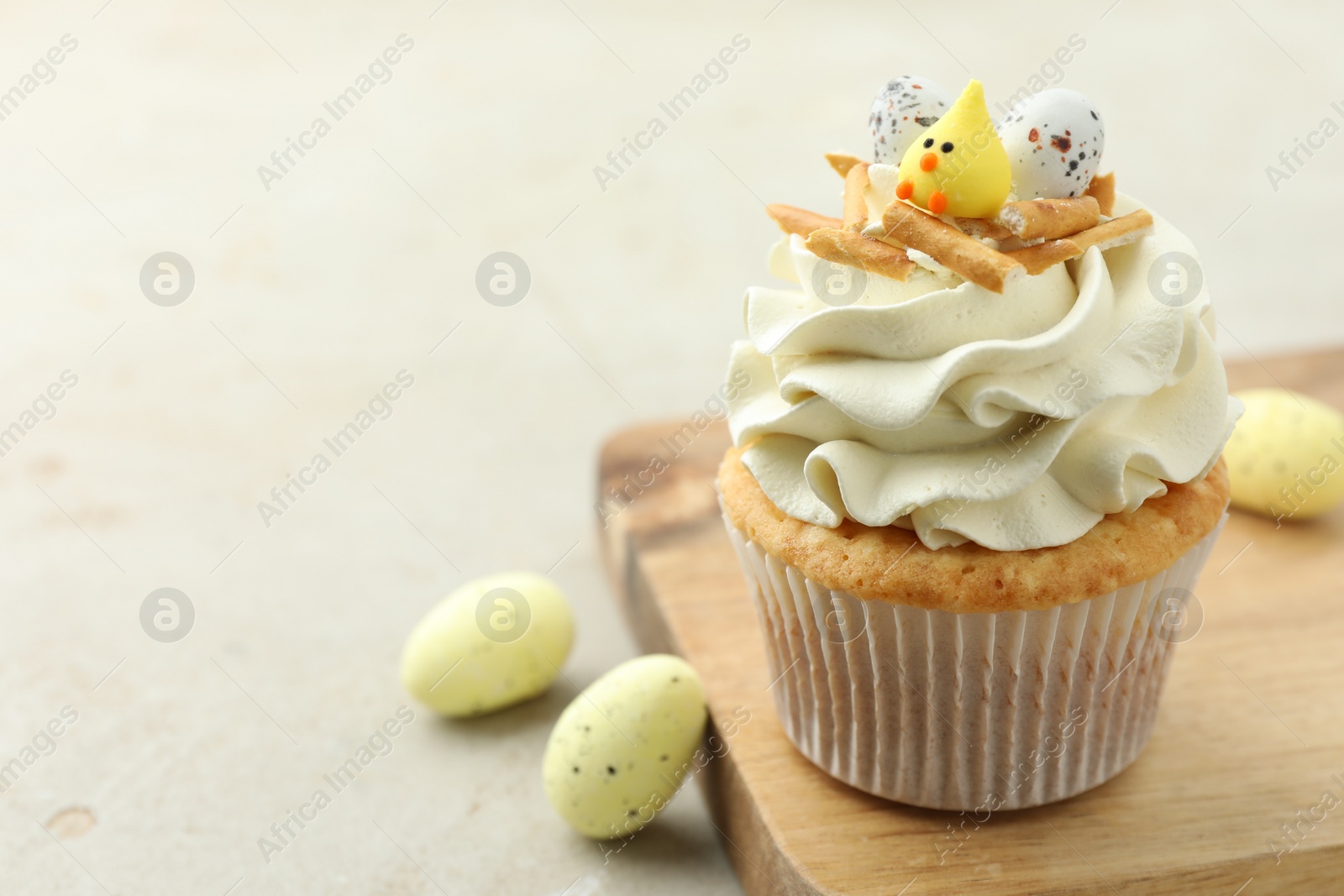 Photo of Tasty Easter cupcake with vanilla cream and candies on gray table, space for text