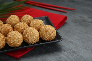 Photo of Many delicious sesame balls on black table, closeup. Space for text