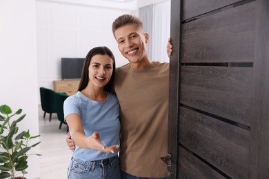 Happy couple welcoming near door. Invitation to come indoors