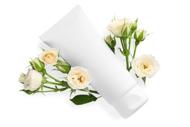 Tube of hand cream and roses on white background, top view