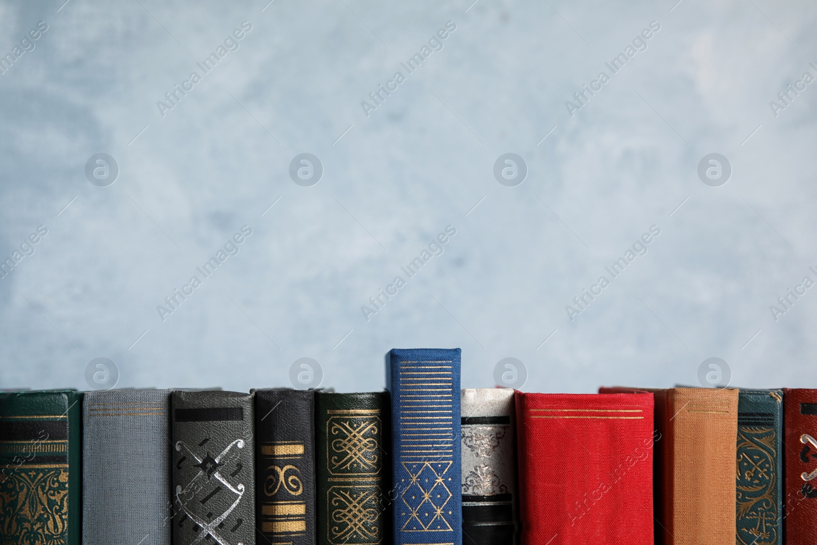 Photo of Stack of hardcover books on light blue background. Space for text