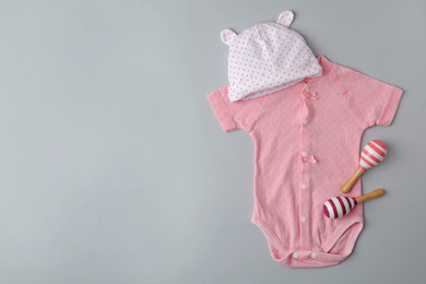 Photo of Child's cap, bodysuit and toys on grey background, flat lay with space for text
