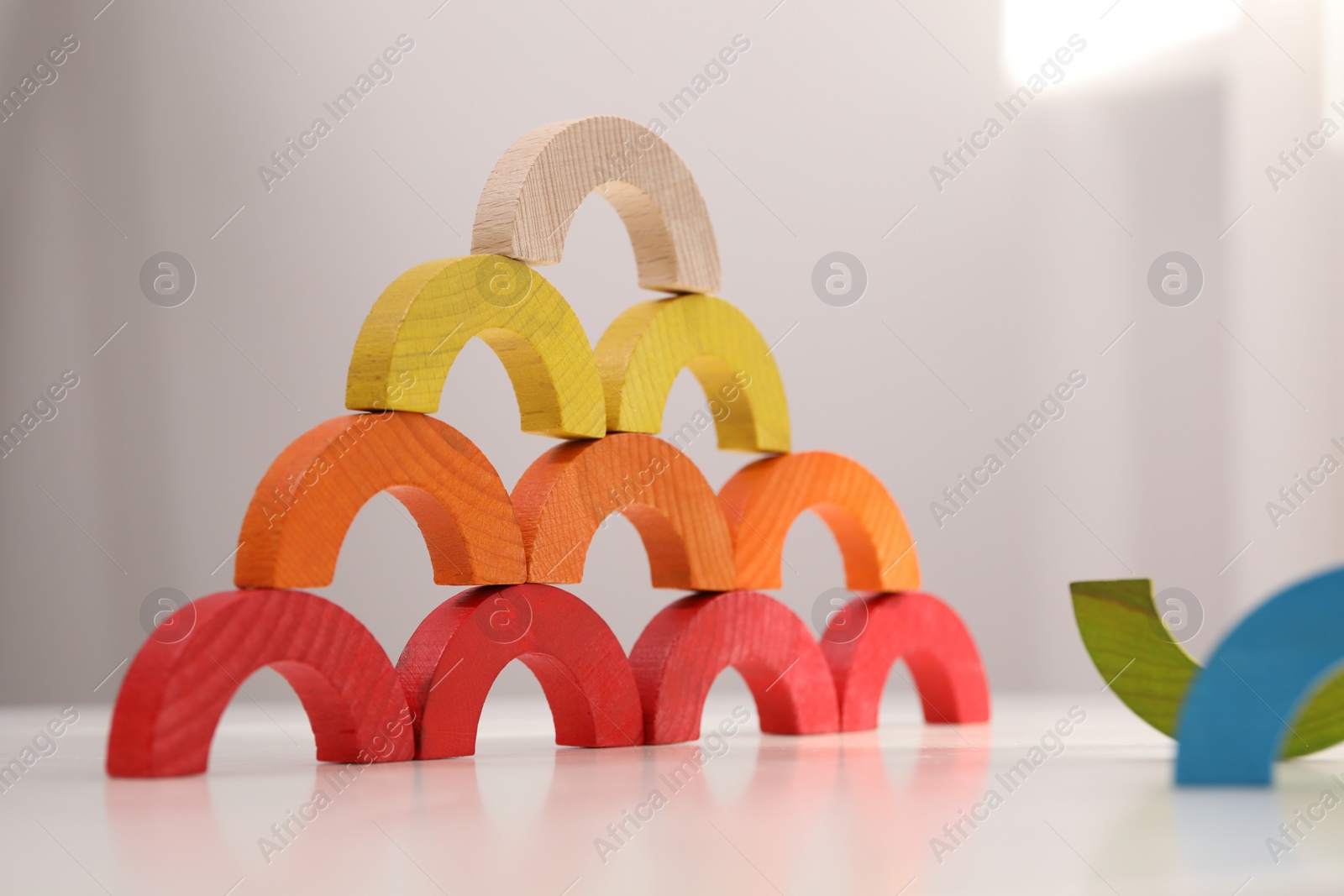 Photo of Colorful wooden pieces of play set on white table indoors. Educational toy for motor skills development