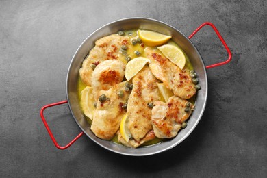 Photo of Delicious chicken piccata with lemons on grey table, top view