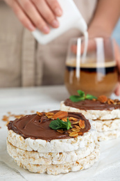 Photo of Puffed rice cakes with chocolate spread on white wooden table