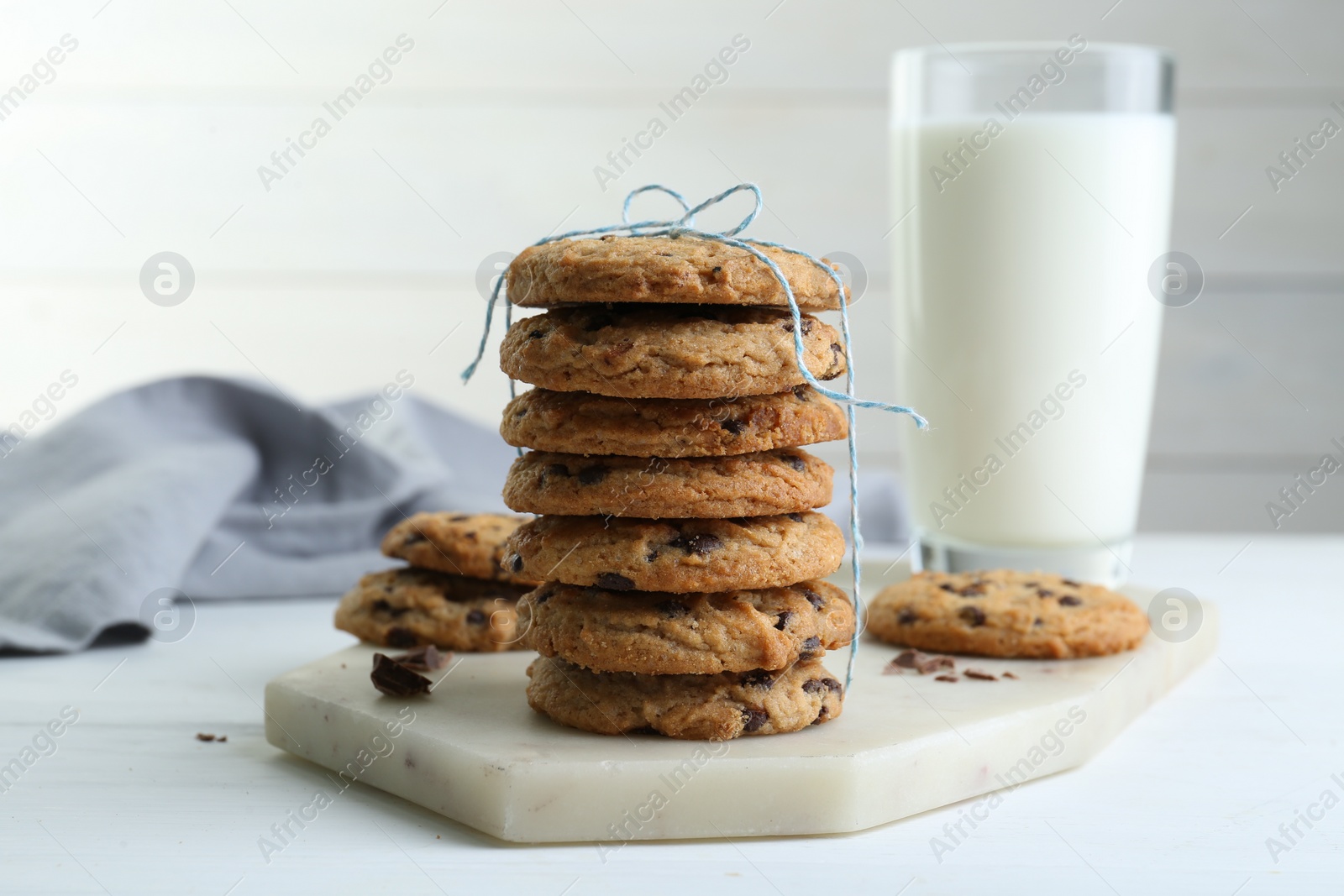 Photo of Tasty chocolate chip cookies and glass of milk on white wooden table, closeup