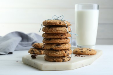 Photo of Tasty chocolate chip cookies and glass of milk on white wooden table, closeup