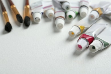 Photo of Brushes and paints on blank canvas, closeup. Space for text
