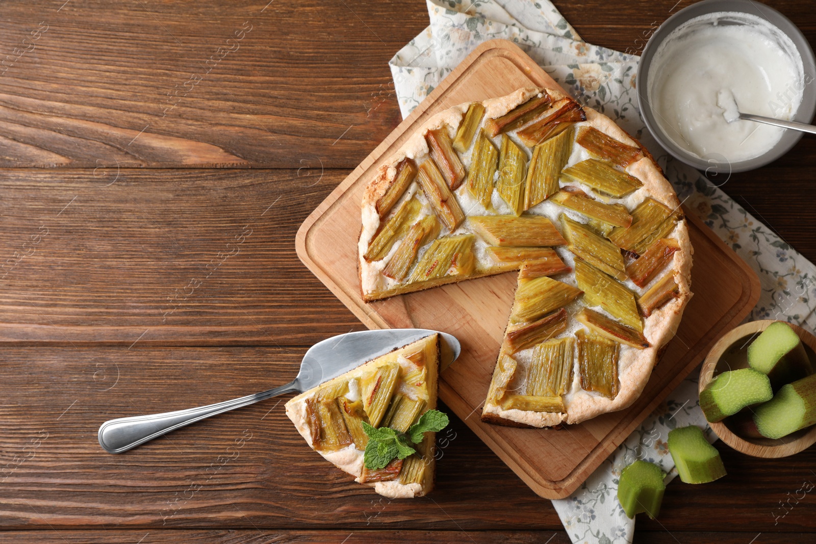 Photo of Freshly baked rhubarb pie with cake server on wooden table, flat lay. Space for text