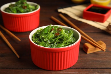 Photo of Japanese seaweed salad served on wooden table, closeup