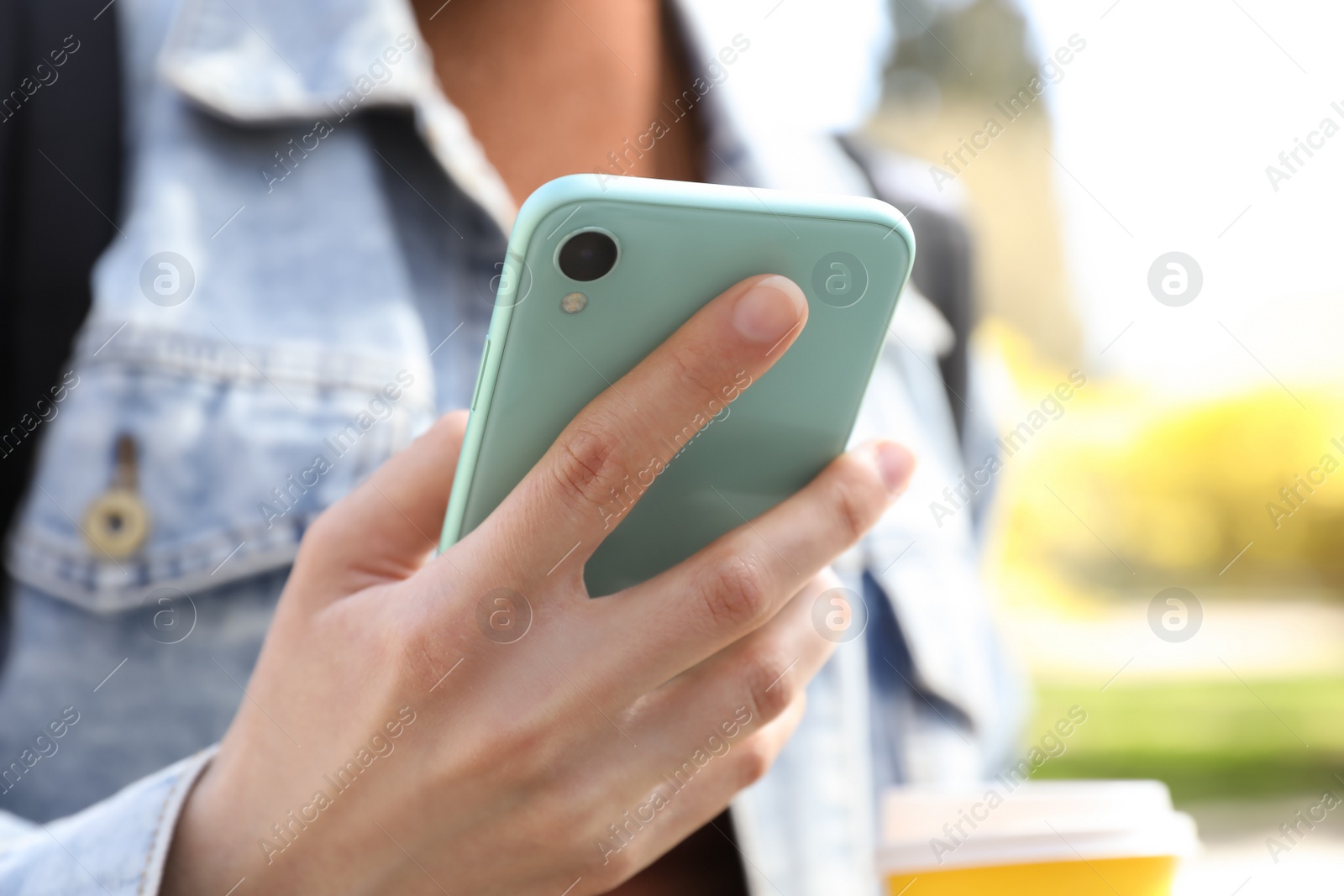 Photo of Woman using smartphone outdoors on sunny day, closeup