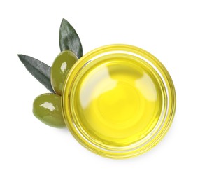 Photo of Cooking oil in bowl, olives and leaves on white background, top view