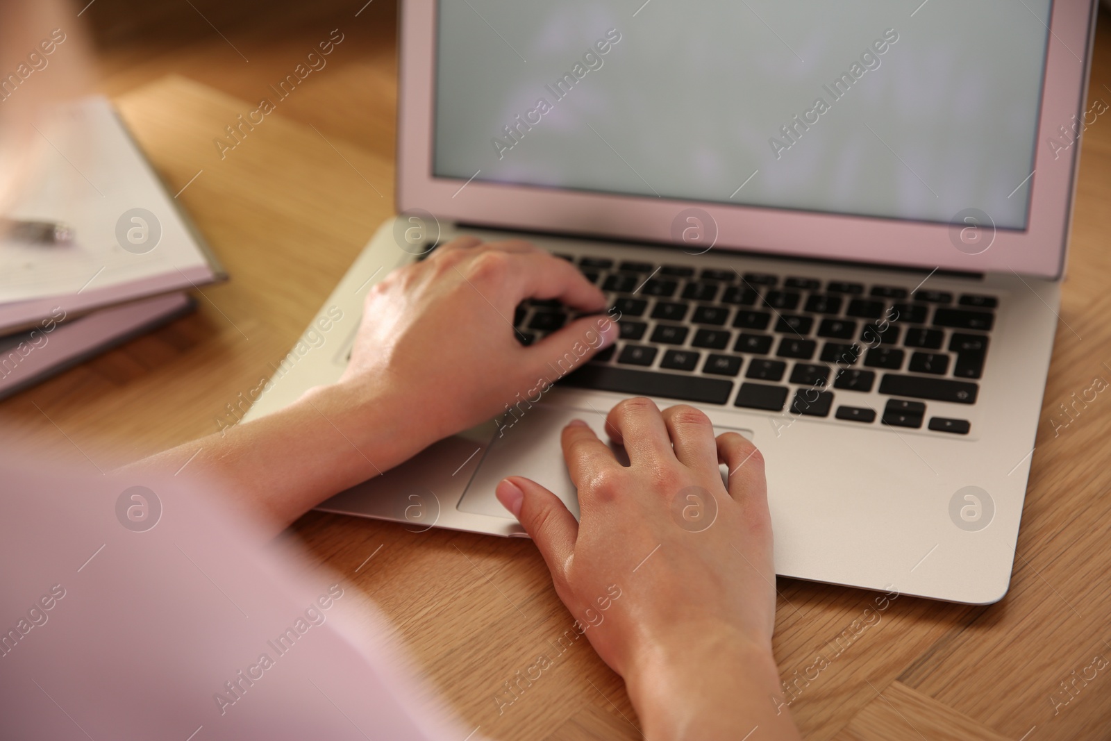 Photo of Woman using modern laptop at wooden table, closeup