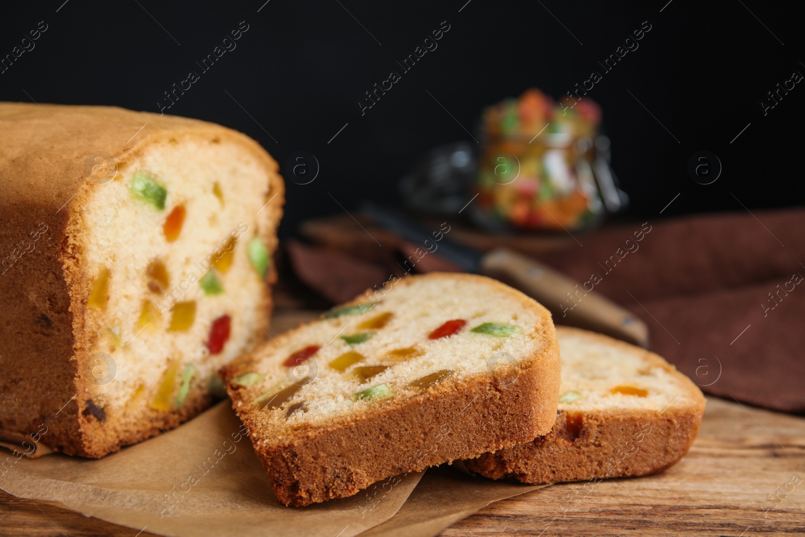 Photo of Delicious cake with candied fruits on wooden table, closeup