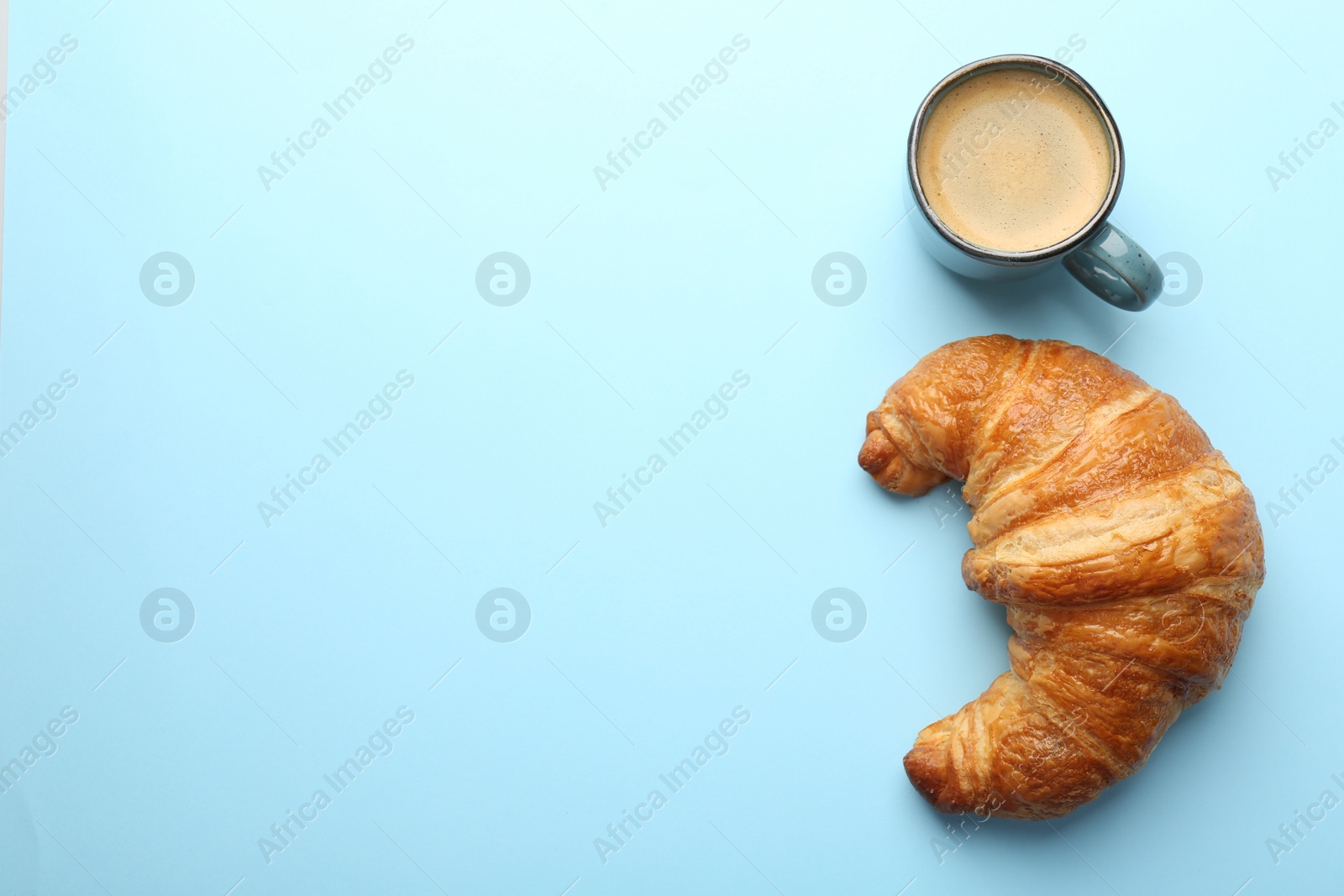 Photo of Delicious fresh croissant and cup of coffee on light blue background, flat lay. Space for text