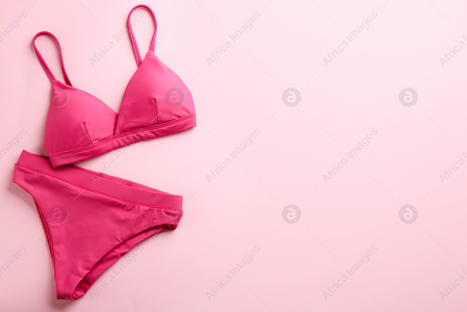 Photo of Beautiful bikini on pink background, top view. Space for text