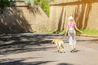 Photo of Young woman and her dog spending time together outdoors. Pet care