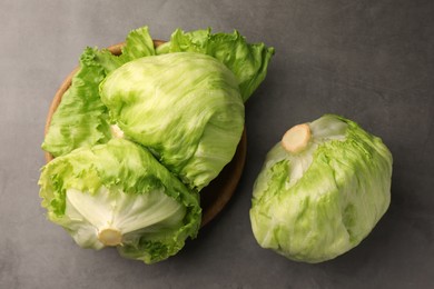 Photo of Fresh green iceberg lettuce heads and leaves on grey table, flat lay