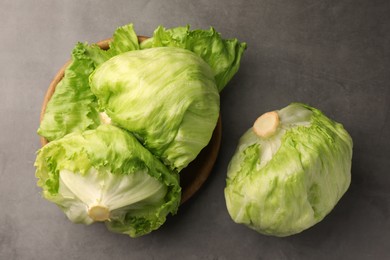 Fresh green iceberg lettuce heads and leaves on grey table, flat lay