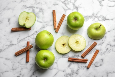 Photo of Fresh apples and cinnamon sticks on marble table, top view