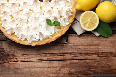 Photo of Flat lay composition with delicious lemon meringue pie on wooden table. Space for text