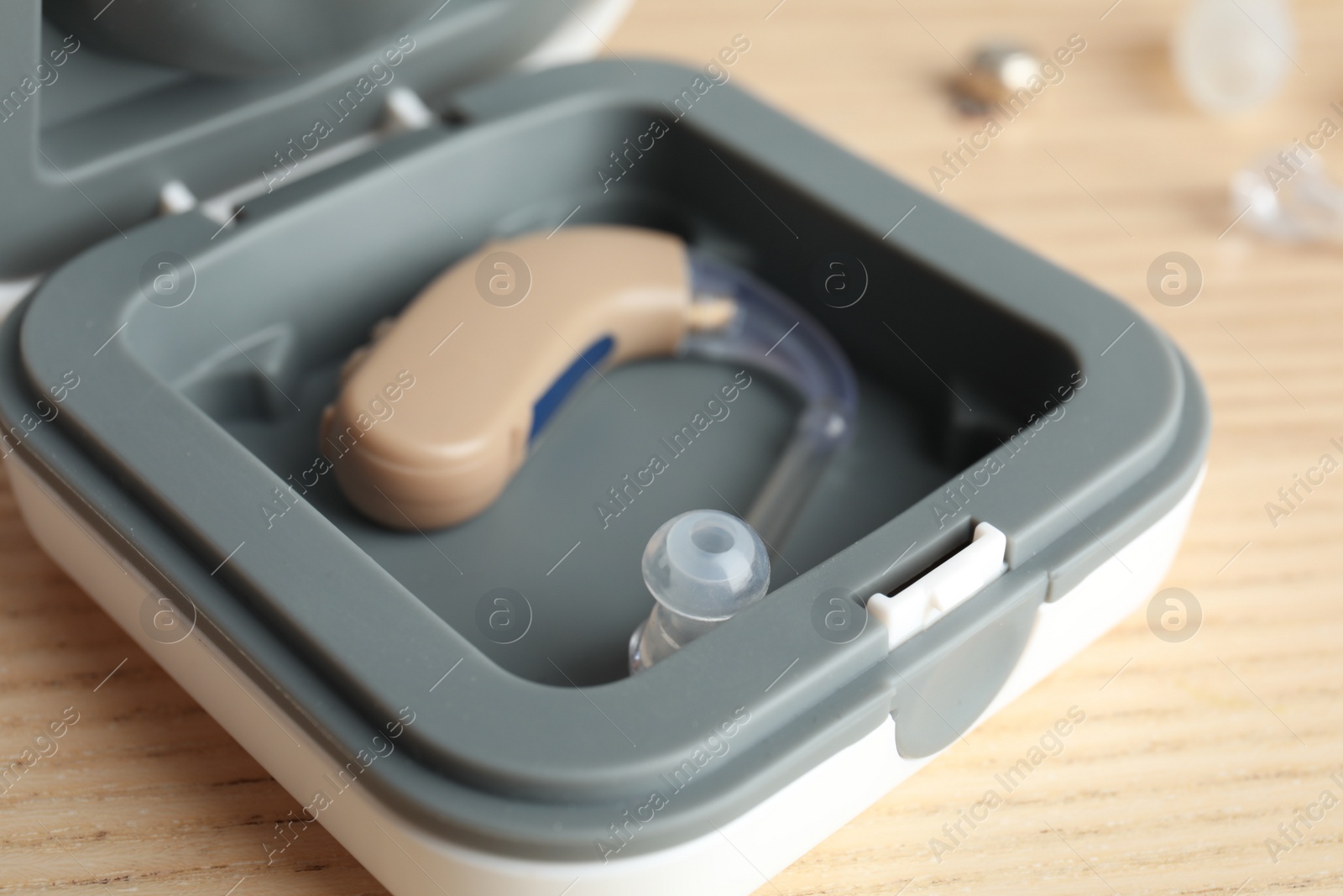 Photo of Case with hearing aid on wooden background, closeup