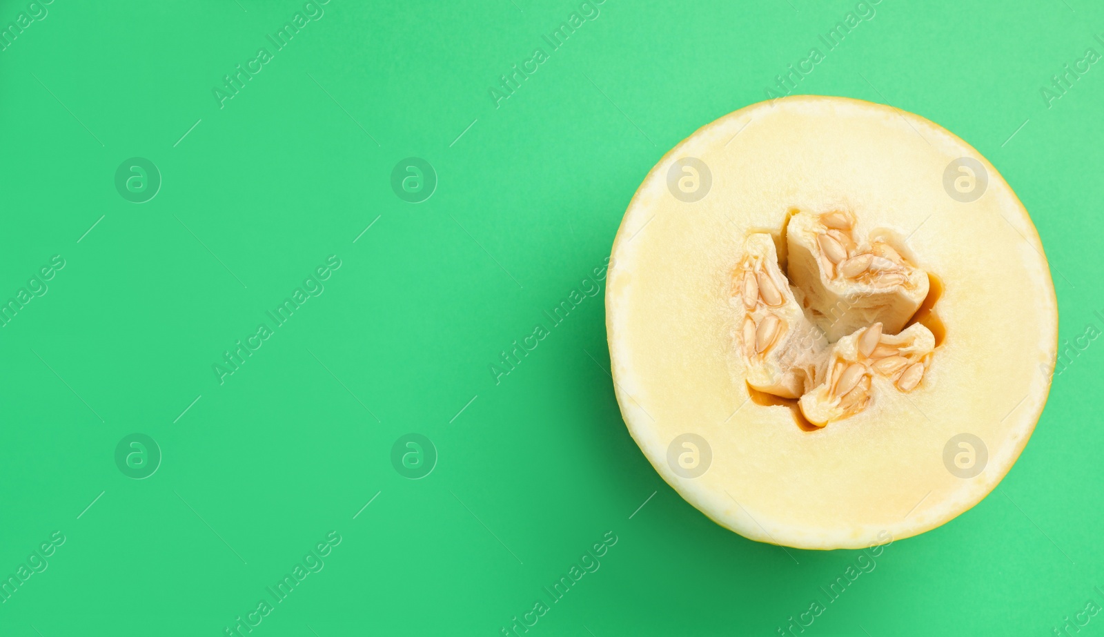 Photo of Half of ripe tasty melon on green background, top view. Space for text