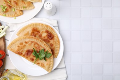 Photo of Delicious fried cheburek with cheese and parsley on white tiled table, flat lay. Space for text