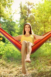 Photo of Happy young woman resting in comfortable hammock at green garden