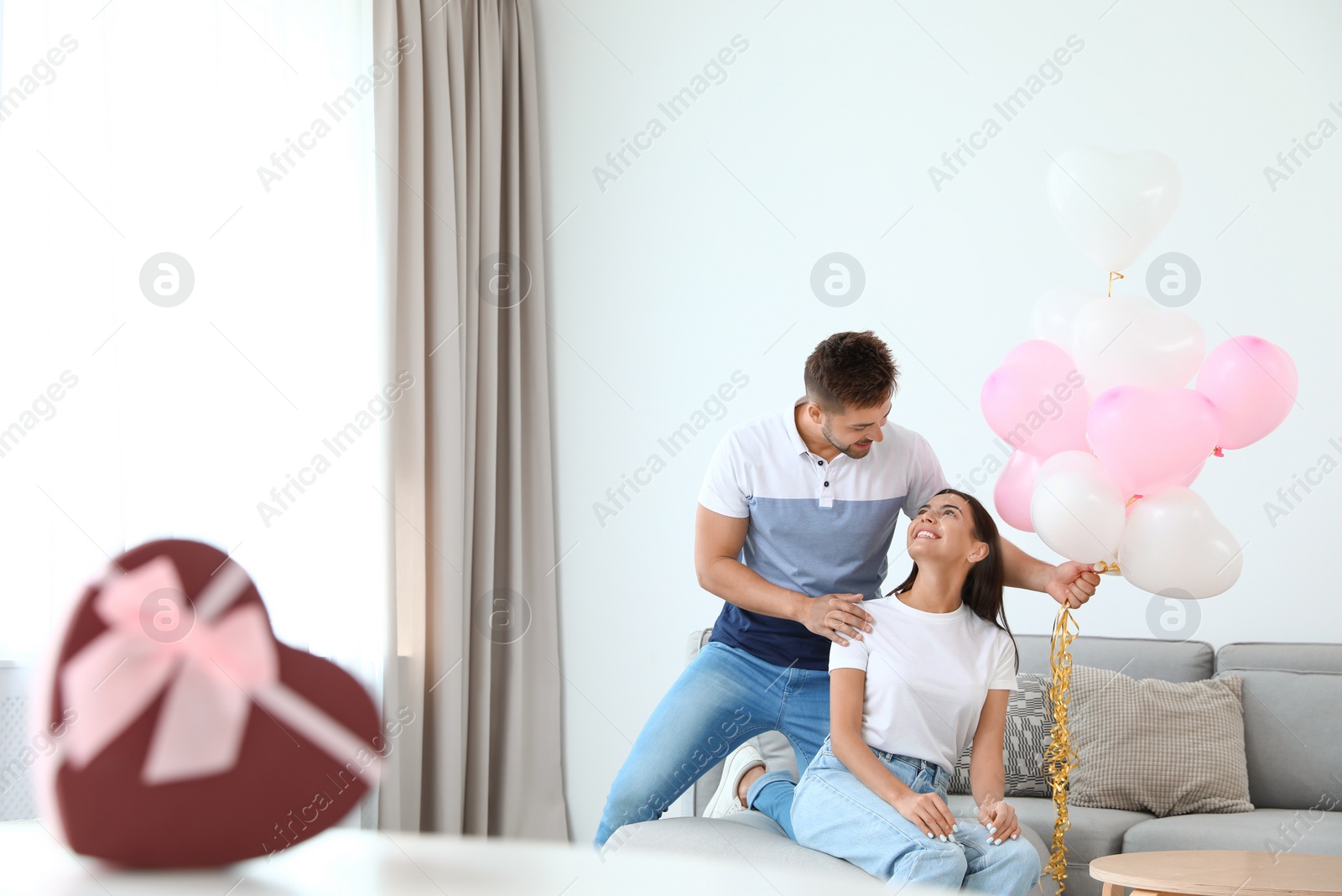 Photo of Young couple with air balloons at home. Celebration of Saint Valentine's Day