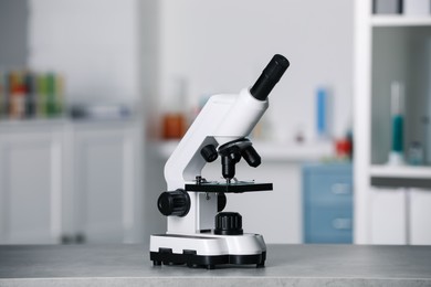 Photo of Modern medical microscope on grey table in laboratory